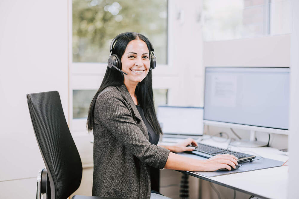 kundenservice-mitarbeiterin-kopfhoerer-bildschirm-seitlich