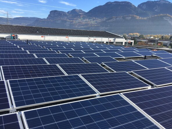 Großflächige Photovoltaikanlage auf einem Flachdach mit Bergpanorama