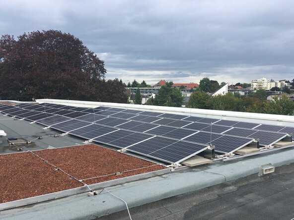 Photovoltaikanlage auf mehreren Gebäudedächern vor Berglandschaft