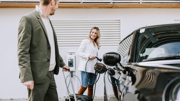 Junges Paar lädt E-Auto an Hotel Wallbox