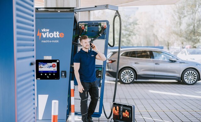 Techniker telefoniert an einem offenen Schnellader und behebt ein Problem