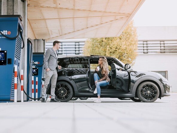 Junges Paar lädt E-Auto an einem Schnelllader