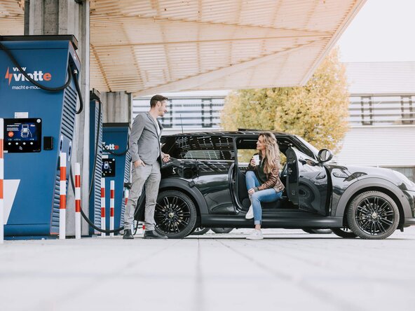 Junges Paar lädt E-Auto an einem Schnelllader
