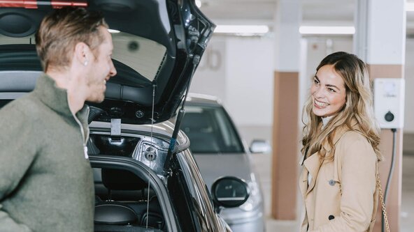 Junges Paar lädt E-Auto an Wallbox in Tiefgarage