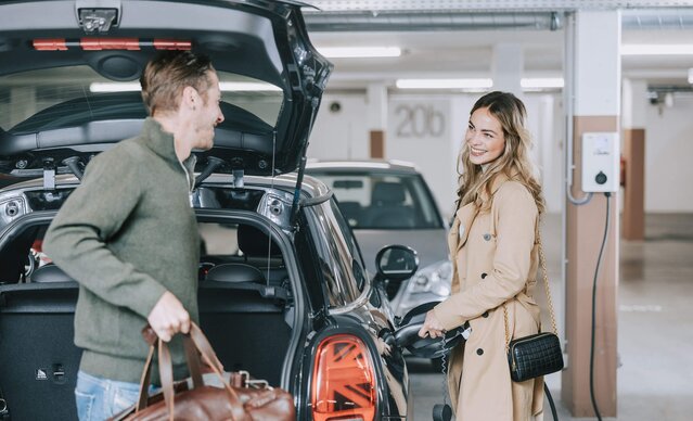Junges Paar lädt E-Auto an Wallbox in Tiefgarage