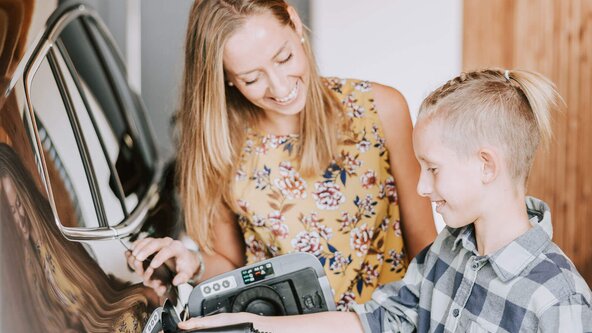 Mutter zeigt ihrem Sohn, wie man ein E-Auto zuhause auflädt