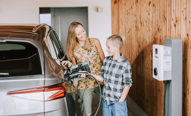 Mutter zeigt ihrem Sohn, wie man ein E-Auto zuhause auflädt