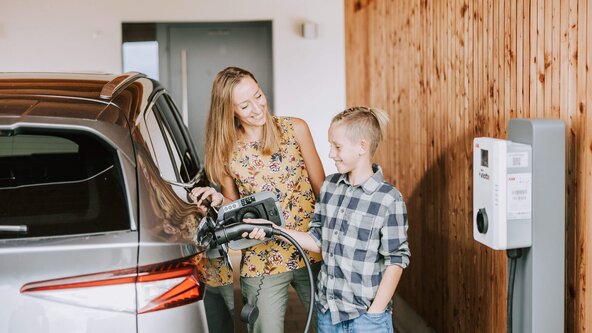 Mutter zeigt ihrem Sohn, wie man ein E-Auto zuhause auflädt
