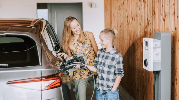 Mutter zeigt ihrem Sohn, wie man ein E-Auto zuhause auflädt