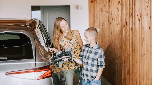 Mutter zeigt ihrem Sohn, wie man ein E-Auto zuhause auflädt