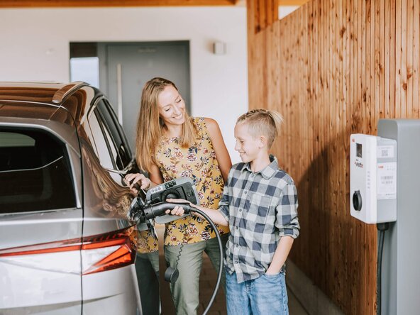 Mutter zeigt ihrem Sohn, wie man ein E-Auto zuhause auflädt