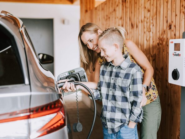 Mutter zeigt ihrem Sohn, wie man ein E-Auto zuhause auflädt
