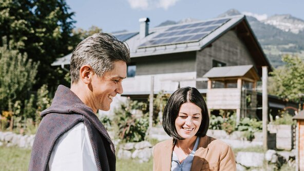 Mann und Frau stehen im Garten und überprüfen auf dem Tablet ihren produzierten Strom mit der PV Anlage