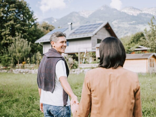 Mann zeigt Frau seine PV Anlage auf dem Dach