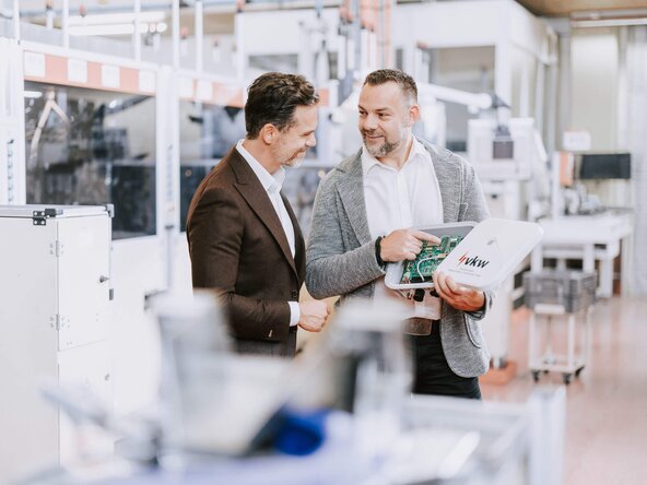 Verkaufsgespräch zwischen Vertriebsmitarbeiter und Kunde in Produktionshalle