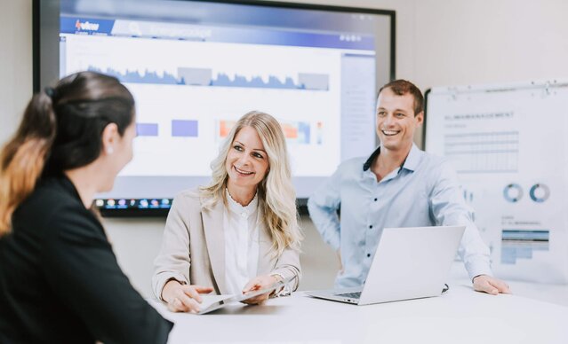 Zwei Frauen und ein Mann haben ein Meeting in einem Besprechungsraum