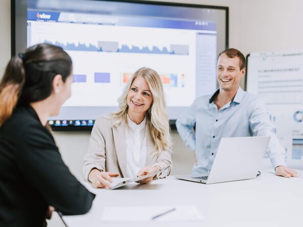 Zwei Frauen und ein Mann haben ein Meeting in einem Besprechungsraum