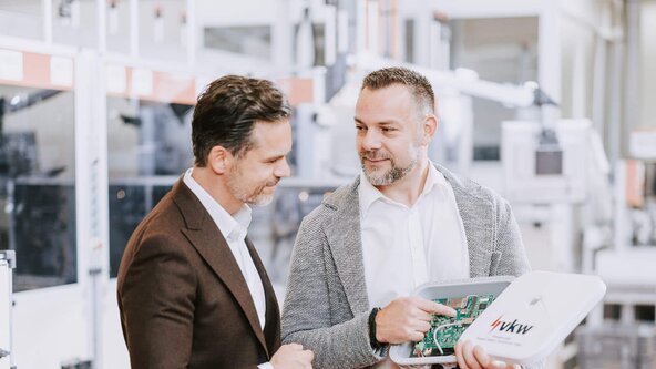 Verkaufsgespräch zwischen Vertriebsmitarbeiter und Kunde in Produktionshalle