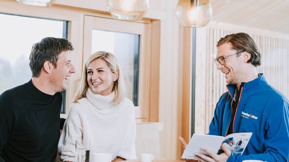 Energieberater sitzt bei Familie am Tisch und zeigt eine Broschüre