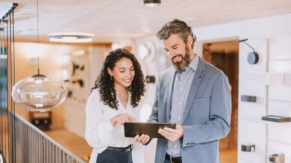 Mann zeigt Frau etwas auf dem Tablet in einem Lampengeschäft