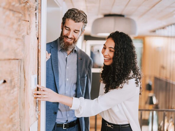 Frau bedient Thermostat an Wand