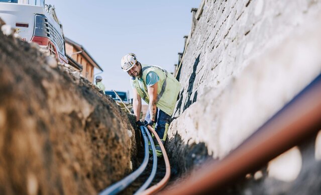 Glasfasermonteur verlegt Glasfaserleitung in Erde