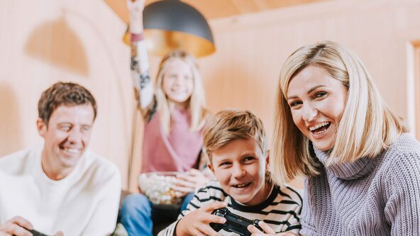 Familie sitzt auf Couch und spielt Playstation