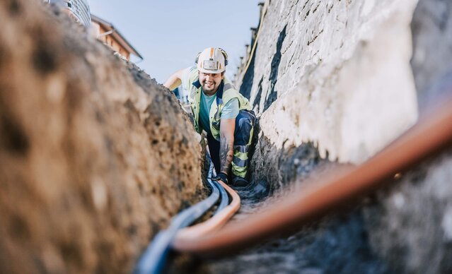 Glasfasermonteur verlegt Glasfaserleitung in Erde