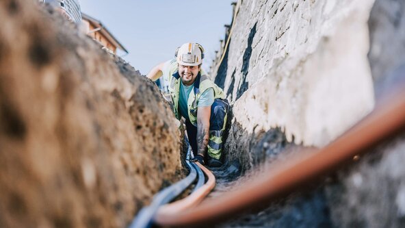 Glasfasermonteur verlegt Glasfaserleitung in Erde