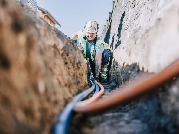 Glasfasermonteur verlegt Glasfaserleitung in Erde