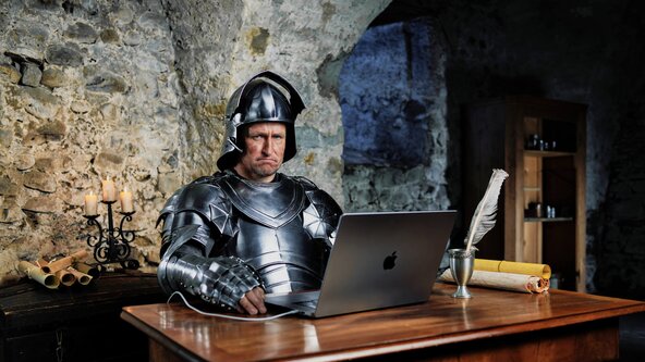 Ritter sitzt mit Laptop am Tisch ohne Glasfaserinternet