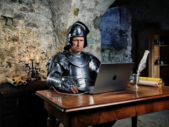 Ritter sitzt mit Laptop am Tisch ohne Glasfaserinternet