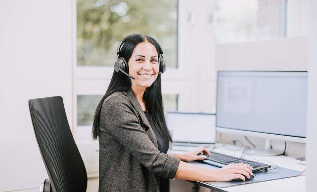 Kundenservicemitarbeiterin sitzt vor dem Bildschirm