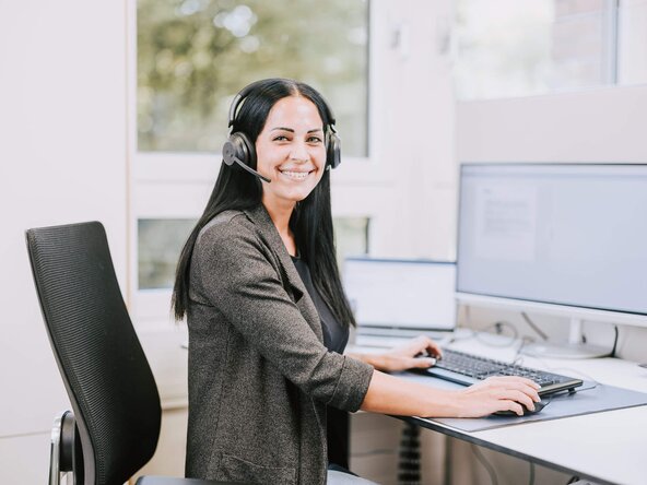 Kundenservicemitarbeiterin sitzt vor dem Bildschirm