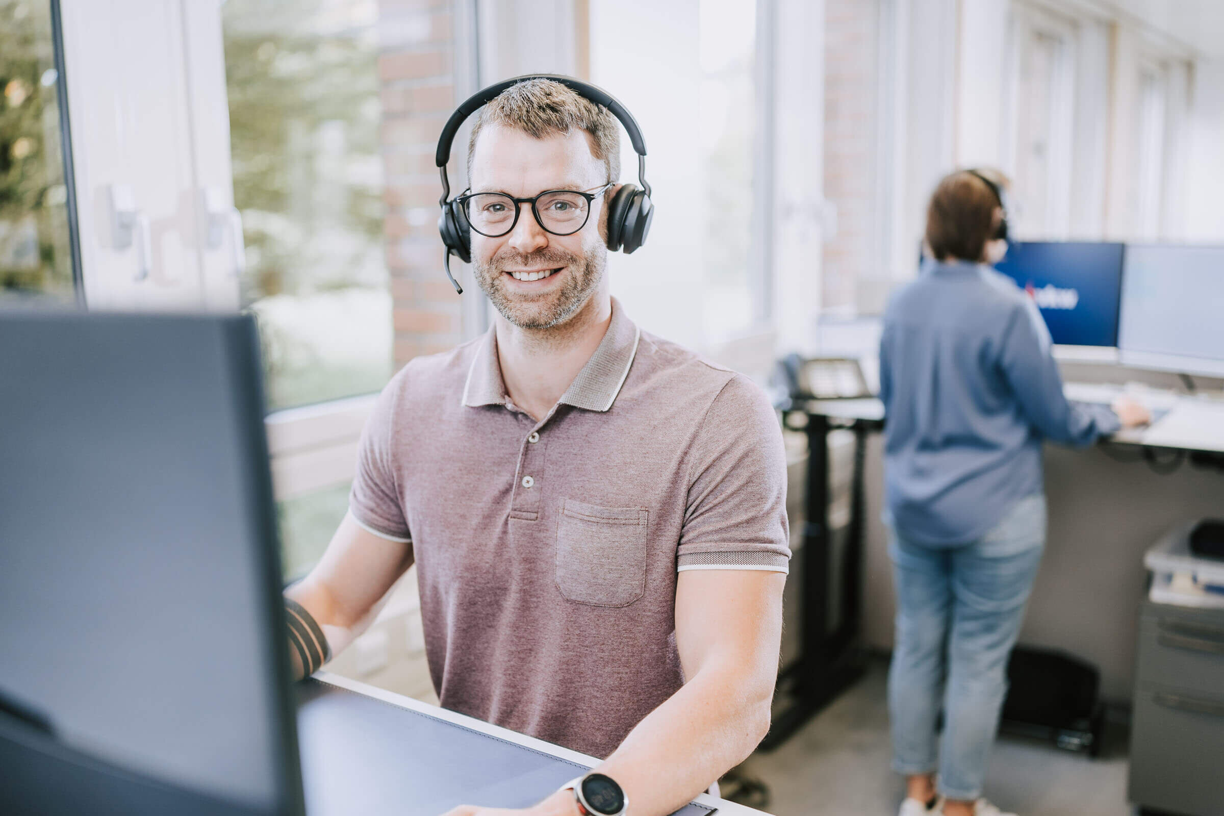 Kundenservicemitarbeiter sitzt mit Headset vor dem Bildschirm