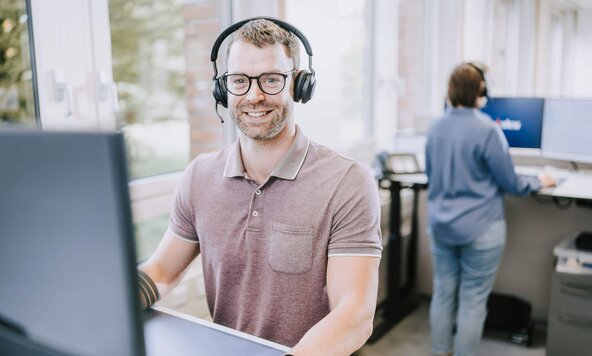 Kundenservicemitarbeiter sitzt mit Headset vor dem Bildschirm