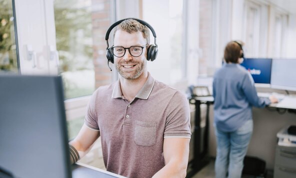 Kundenservicemitarbeiter sitzt mit Headset vor dem Bildschirm