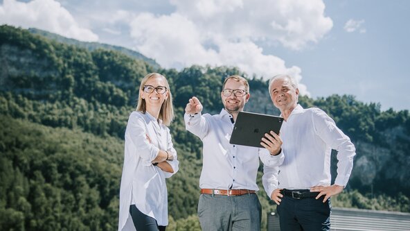 Drei Personen stehen auf dem Dach und begutachten die PV Anlage