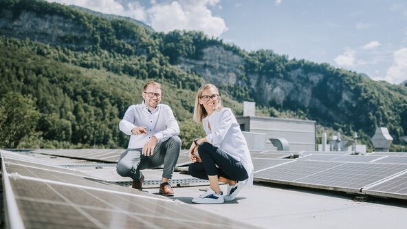Ein Mann zeigt einer Frau die PV Anlage auf dem Dach