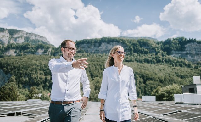 Ein Mann zeigt einer Frau die PV Anlage auf dem Dach