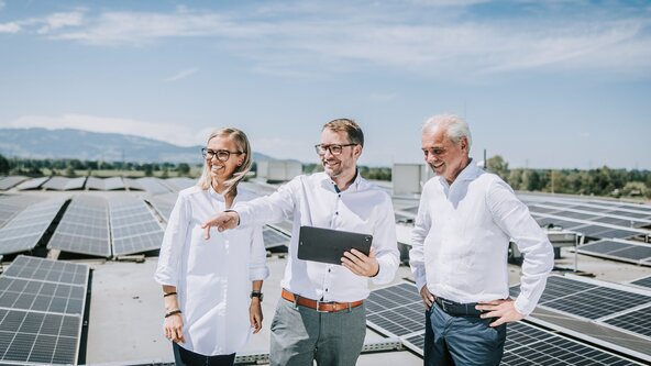 Mann mit Tablet zeigt seinen Kunden die Leistung der PV Anlage