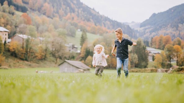 Zwei Kinder spielen mit einem Drachen auf der Wiese
