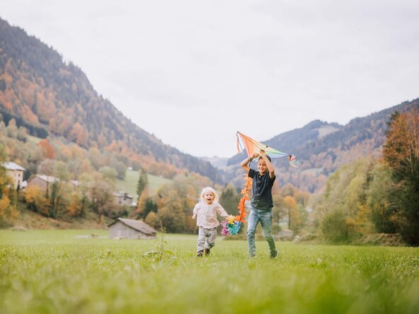 Zwei Kinder spielen mit einem Drachen auf der Wiese