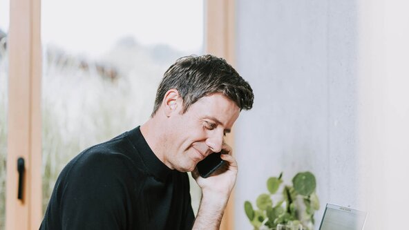 Mann telefoniert mit Handy an Schreibtisch