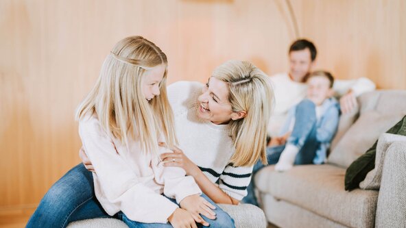 Familie sitzt auf Couch in Wohnzimmer