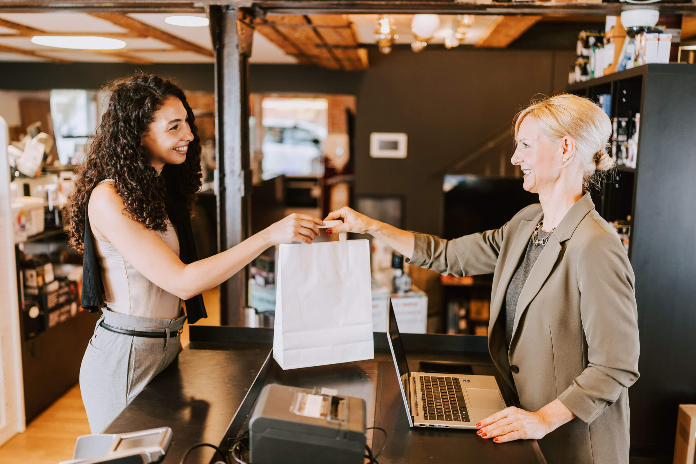 Ladenbesitzerin gibt Kundin eine weiße Tasche
