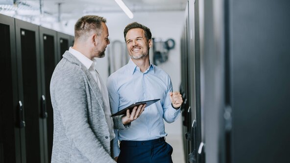 Unternehmer zeigt Kundenbetreuer seinen Serverschrank
