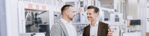Kundenbetreuer führt Gespräch mit Unternehmer in Produktionshalle