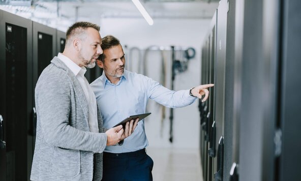 Kundenbetreuer führt Gespräch mit Unternehmer vor Serverschränke