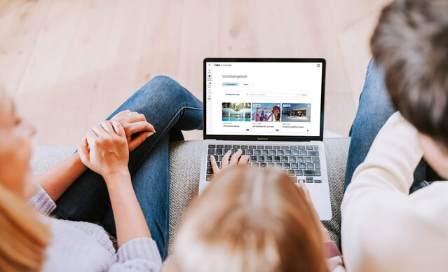 Familie sitzen auf Couchtisch sieht in Laptop